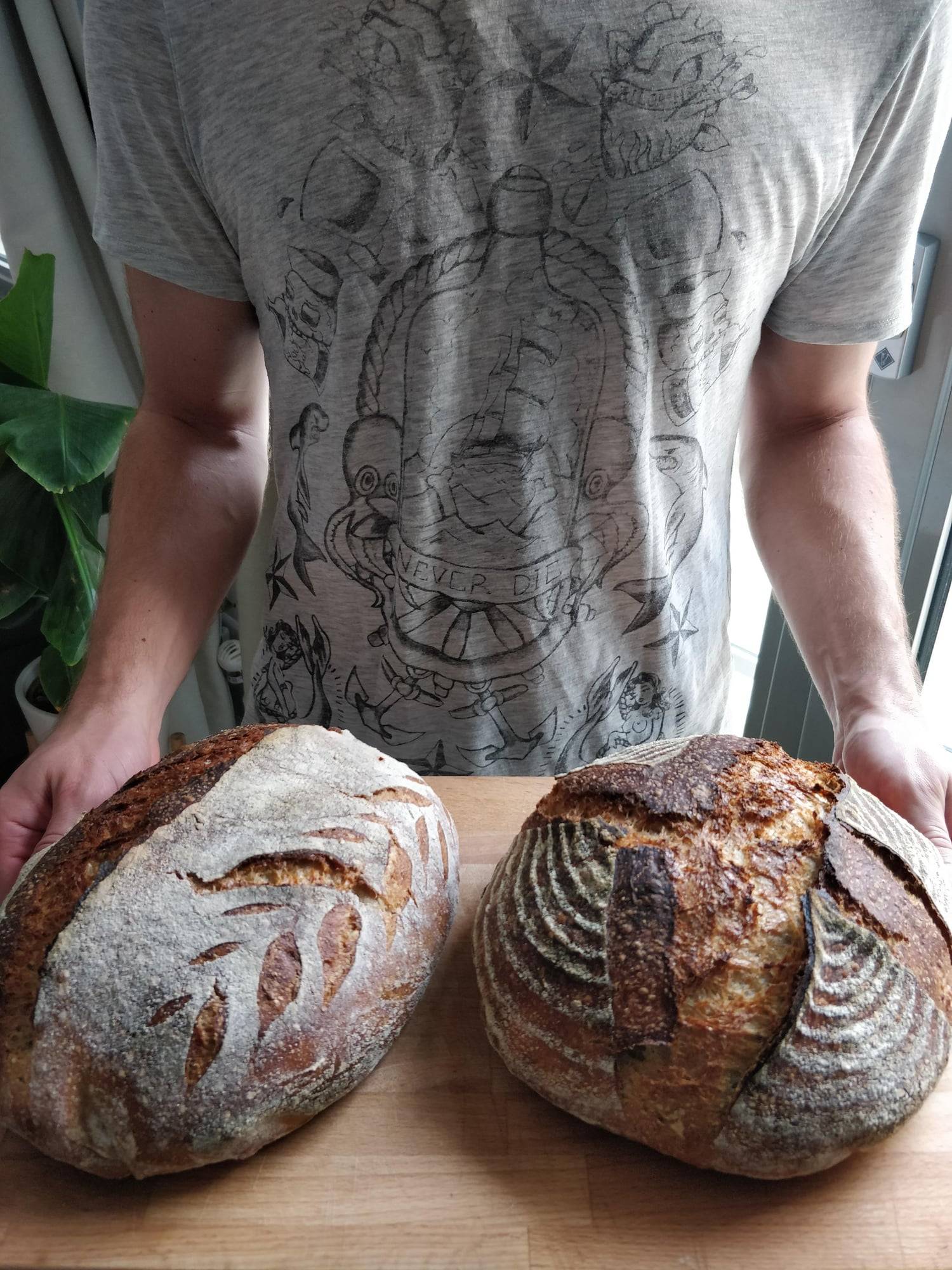 Eugene holding two freshly baked sourdough loaves.