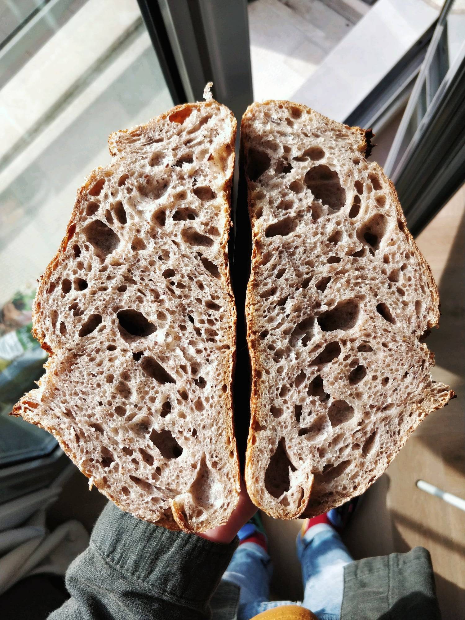A sourdough loaf cut in half, showing an open, irregular crumb.